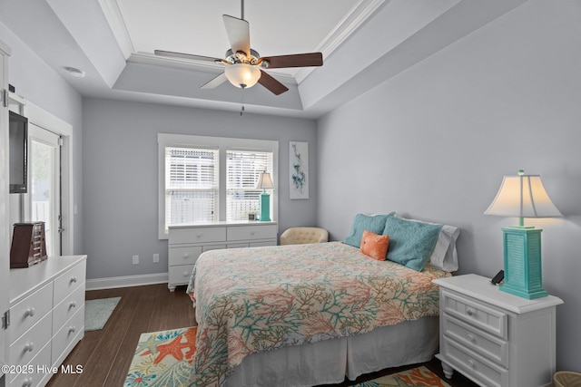 bedroom with dark wood-style floors, baseboards, a tray ceiling, and ornamental molding