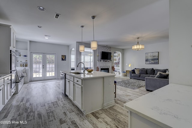 kitchen with french doors, a fireplace, visible vents, appliances with stainless steel finishes, and a sink