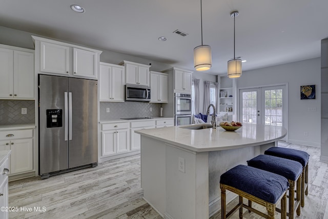 kitchen with stainless steel appliances, french doors, white cabinetry, and a sink