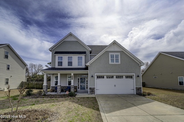 craftsman inspired home with covered porch, fence, a garage, stone siding, and driveway