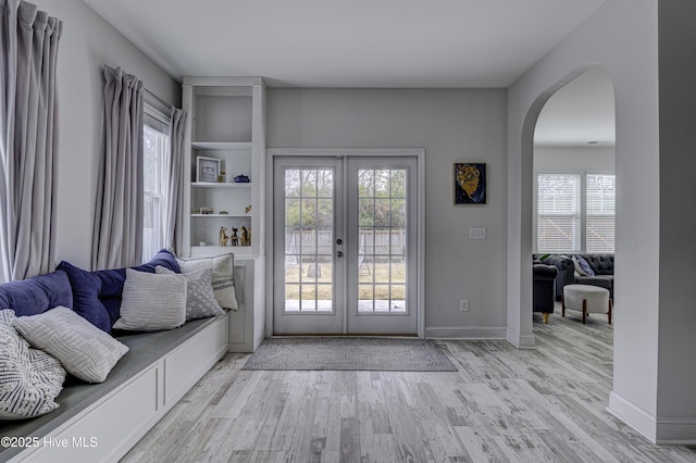 doorway to outside featuring arched walkways, french doors, baseboards, and wood finished floors