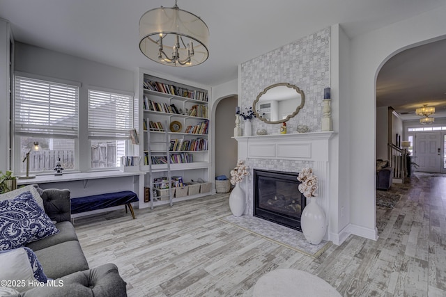 living area featuring a notable chandelier, arched walkways, and wood finished floors