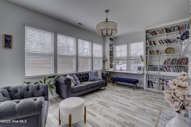 living room featuring baseboards, visible vents, an inviting chandelier, and wood finished floors