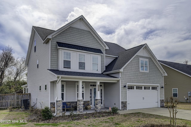 view of front of house featuring a garage, stone siding, covered porch, and fence