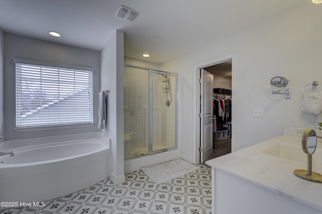 bathroom featuring tile patterned floors, a walk in closet, a shower stall, a bath, and recessed lighting