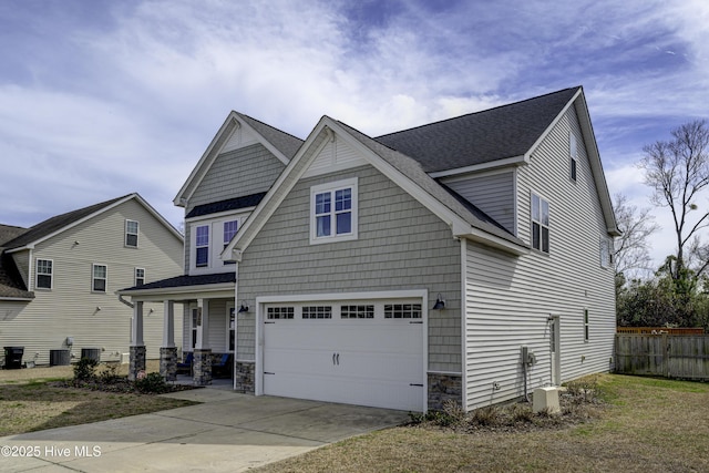 craftsman inspired home with a garage, driveway, stone siding, fence, and central air condition unit