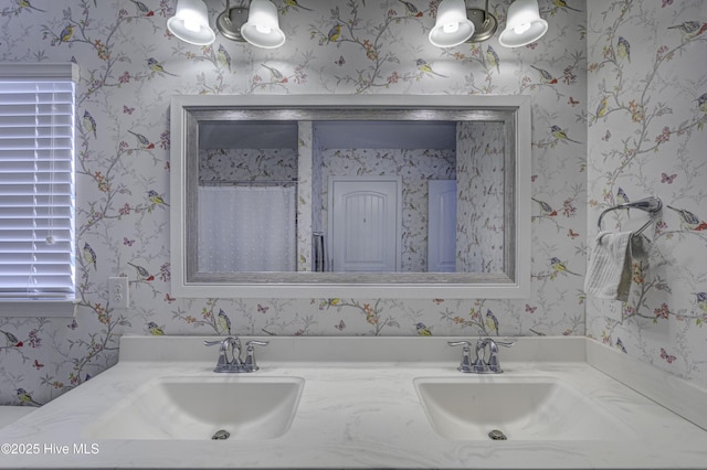 bathroom with double vanity, wallpapered walls, and a sink