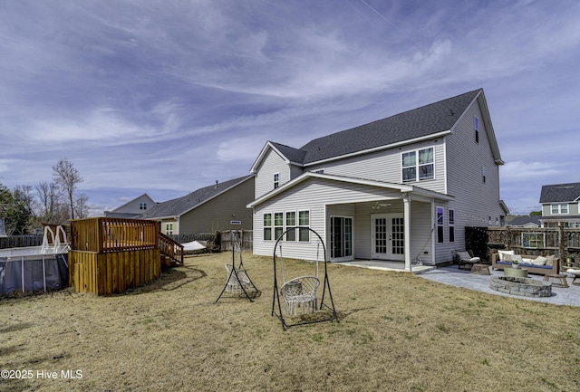 rear view of property featuring a deck, a patio, a fenced backyard, a yard, and french doors