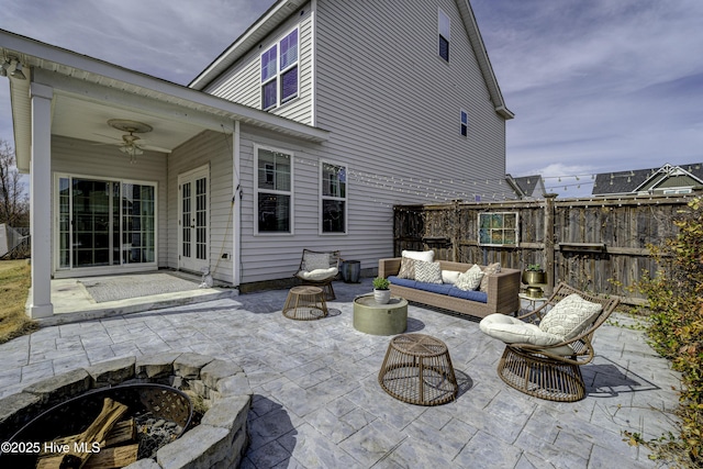 view of patio with ceiling fan, fence, and an outdoor living space with a fire pit