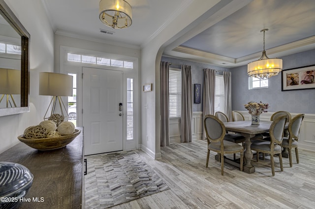 entrance foyer featuring light wood finished floors, visible vents, wainscoting, crown molding, and a decorative wall