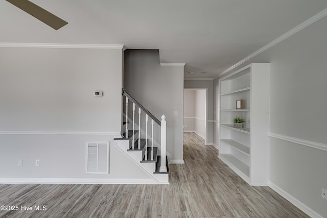 staircase with baseboards, visible vents, ornamental molding, wood finished floors, and built in shelves