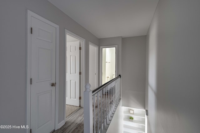 hall featuring wood finished floors and an upstairs landing