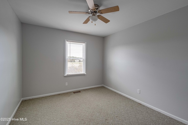 spare room with carpet, visible vents, baseboards, and a ceiling fan