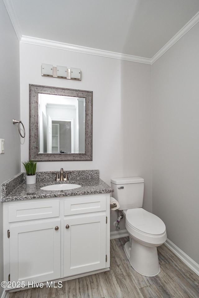 bathroom with toilet, wood finished floors, vanity, baseboards, and ornamental molding