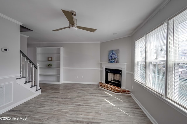 living room with crown molding, visible vents, a fireplace, and stairway