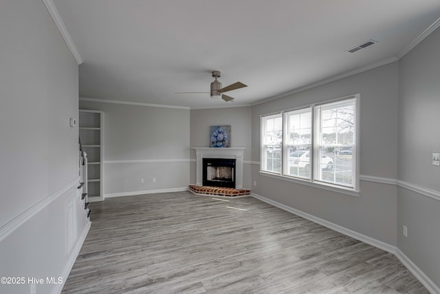 unfurnished living room featuring light wood-style flooring, a fireplace, visible vents, baseboards, and crown molding