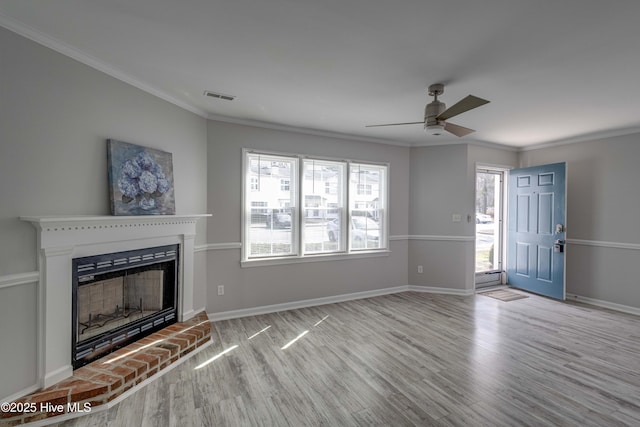 unfurnished living room featuring ornamental molding, a brick fireplace, wood finished floors, and visible vents