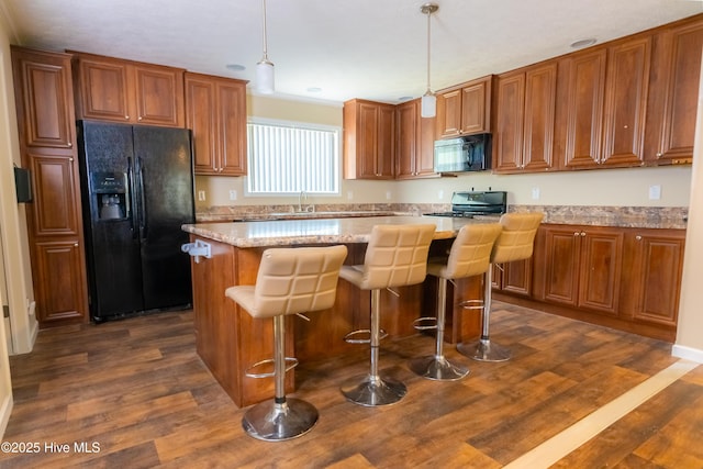 kitchen with dark wood-style floors, brown cabinets, a kitchen island, and black appliances