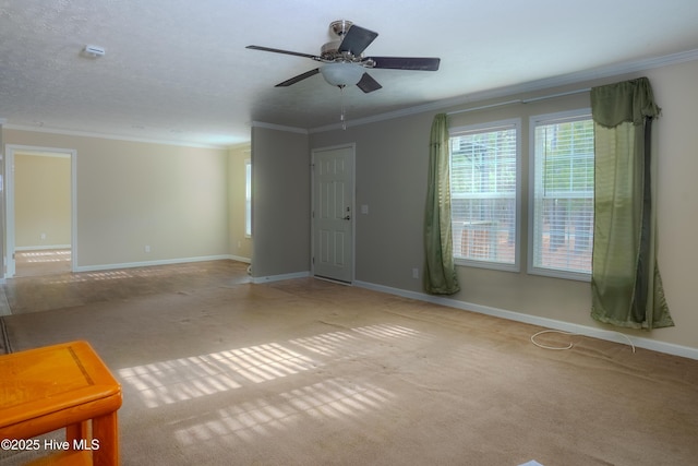 empty room featuring ornamental molding, carpet flooring, baseboards, and a ceiling fan