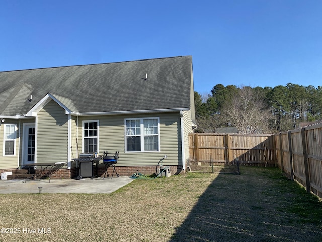 rear view of property with roof with shingles, a fenced backyard, a yard, and a patio