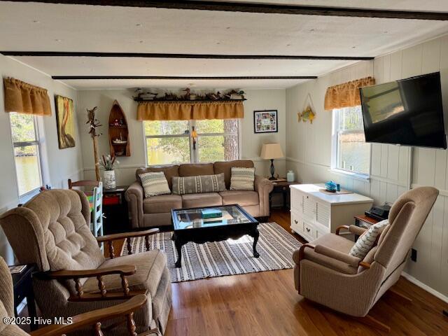 living room with a healthy amount of sunlight, beam ceiling, and wood finished floors