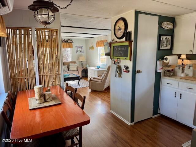 dining space with a wall unit AC and wood finished floors