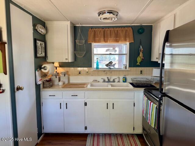 kitchen with range with electric cooktop, a sink, white cabinetry, light countertops, and freestanding refrigerator