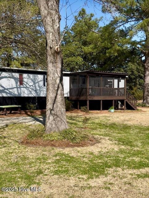 rear view of house with a sunroom, a yard, and stairway