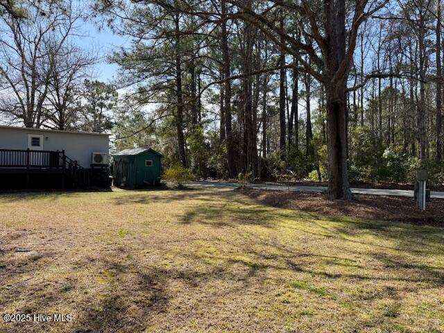 view of yard featuring an outbuilding, a wooden deck, and a shed