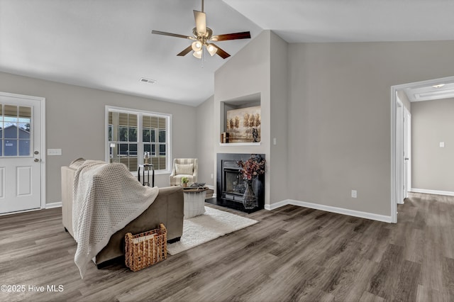 living area featuring a fireplace with flush hearth, visible vents, and wood finished floors