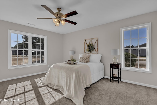 carpeted bedroom with visible vents, ceiling fan, baseboards, and multiple windows