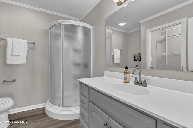 bathroom featuring ornamental molding, a stall shower, wood finished floors, and vanity