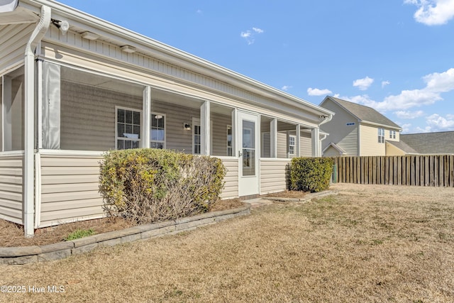 view of front of property featuring a sunroom, fence, and a front yard