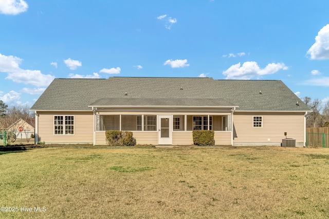 rear view of property with roof with shingles, a yard, central AC unit, a sunroom, and fence