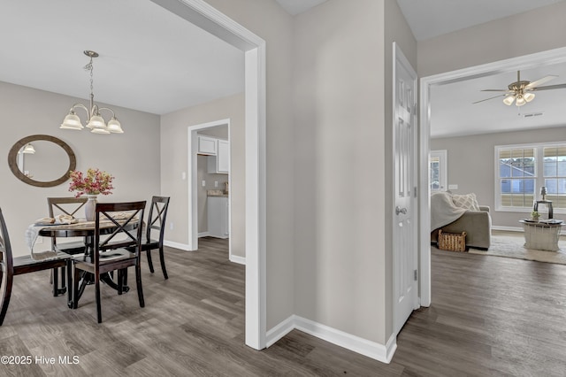 dining space with visible vents, baseboards, wood finished floors, and ceiling fan with notable chandelier