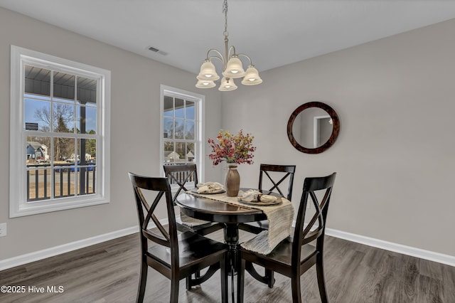 dining space featuring a notable chandelier, baseboards, visible vents, and dark wood-style flooring