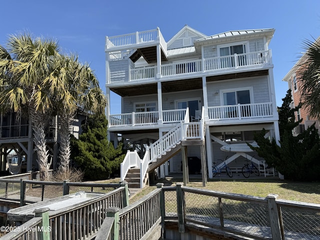 rear view of property with metal roof, a fenced backyard, stairway, a lawn, and a standing seam roof