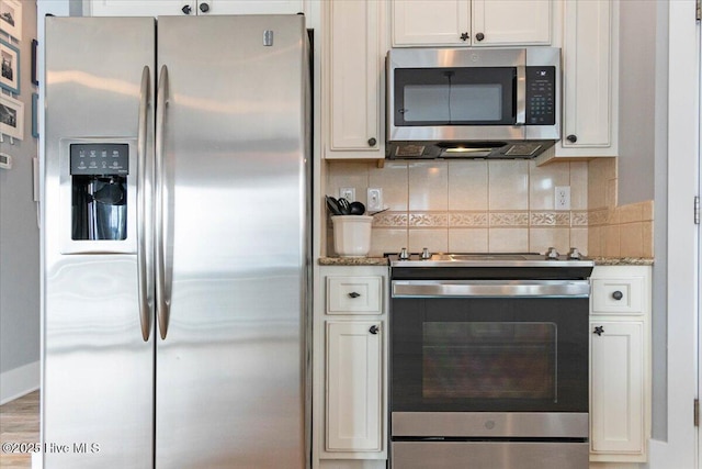 kitchen with tasteful backsplash, white cabinets, stainless steel appliances, and light stone countertops