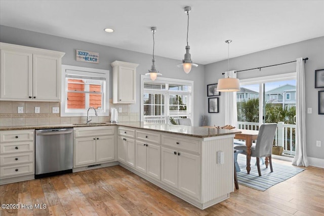 kitchen with white cabinets, dishwasher, light wood-style flooring, a peninsula, and a sink