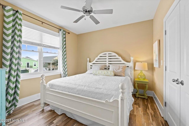 bedroom with ceiling fan, baseboards, and wood finished floors