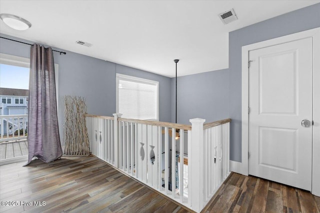 hallway with plenty of natural light, wood finished floors, and visible vents