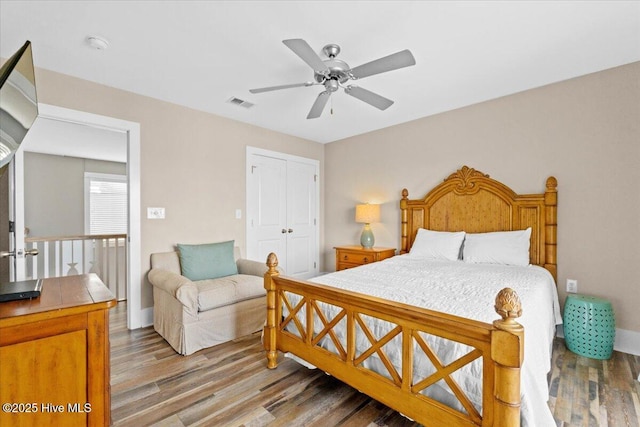 bedroom with wood finished floors, visible vents, a closet, and ceiling fan