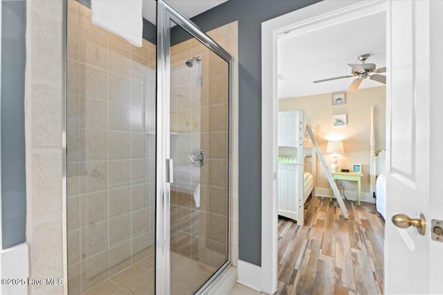 bathroom featuring connected bathroom, baseboards, a stall shower, wood finished floors, and a ceiling fan