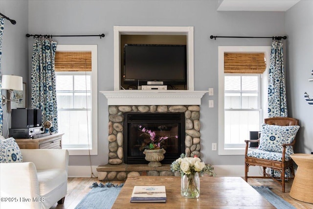 living area featuring a stone fireplace and wood finished floors