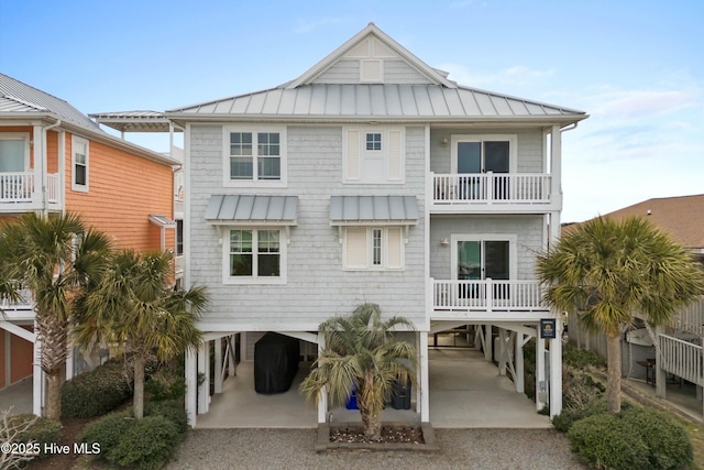 view of front of home featuring metal roof, a balcony, a carport, driveway, and a standing seam roof