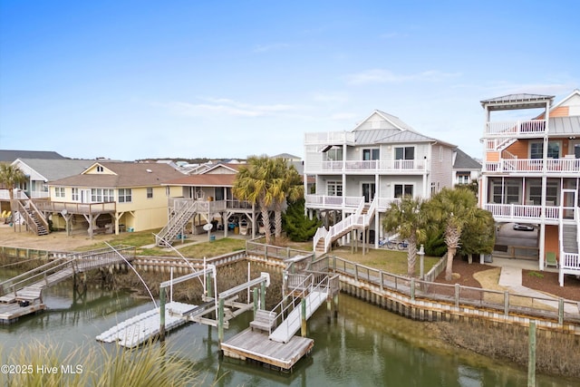 view of dock with a residential view, a water view, boat lift, and stairs