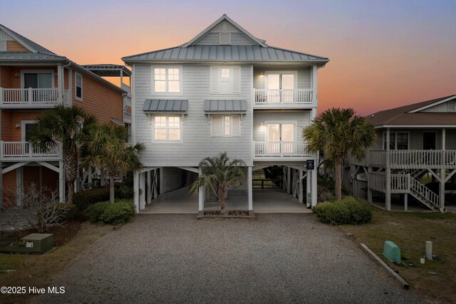 raised beach house with a carport, metal roof, gravel driveway, and a standing seam roof