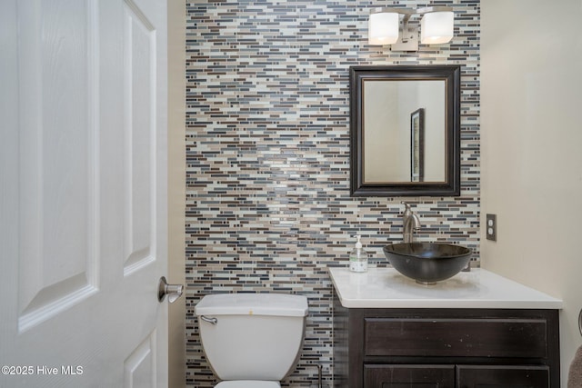 half bathroom featuring toilet, tasteful backsplash, and vanity