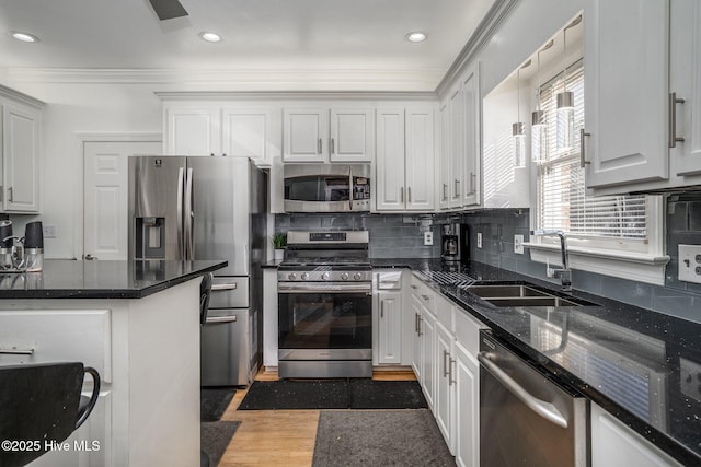 kitchen featuring crown molding, backsplash, appliances with stainless steel finishes, white cabinets, and a sink