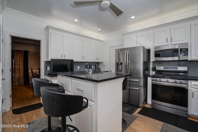 kitchen featuring ceiling fan, light wood-style flooring, stainless steel appliances, ornamental molding, and backsplash